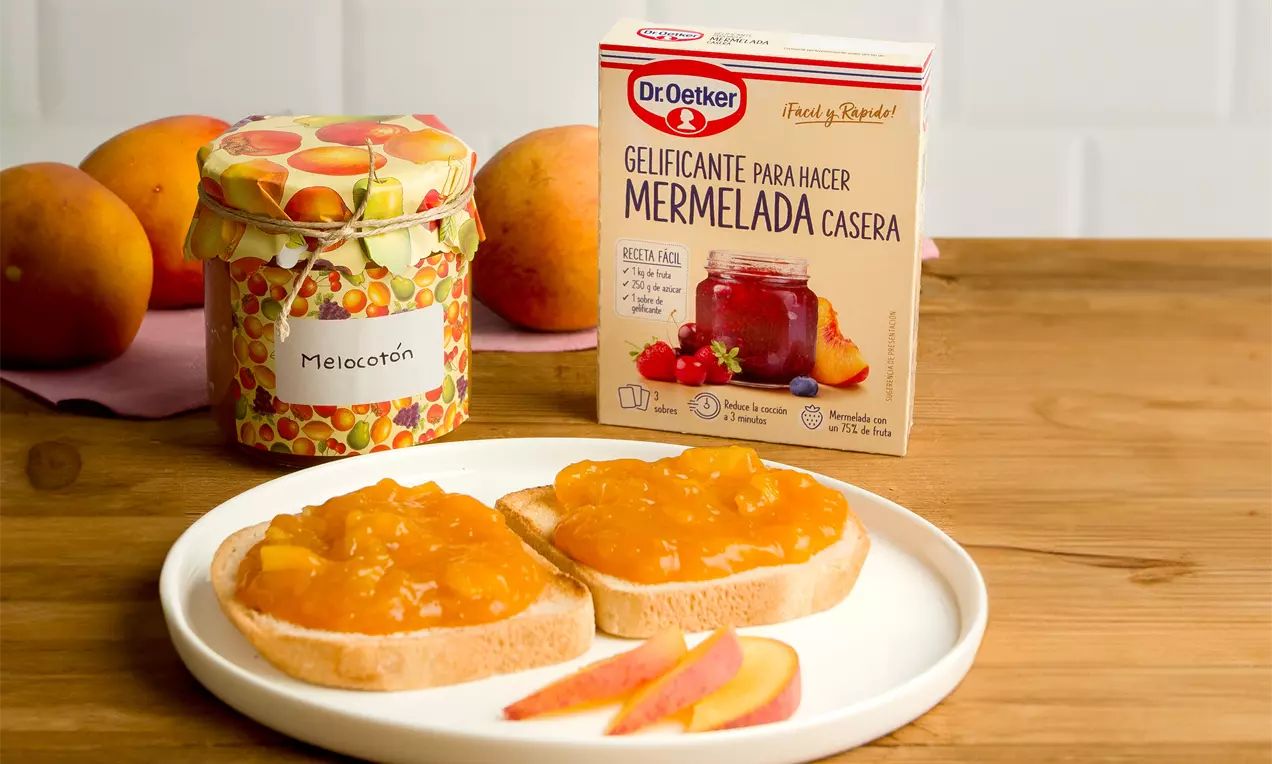 Tostadas doradas cubiertas con mermelada de melocotón de color anaranjado brillante, acompañadas de rodajas finas y melocotones al fondo